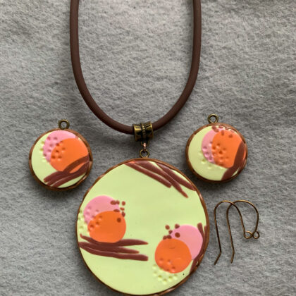 photo of casual jewelry necklace and earring set of yellow polymer clay with orange, brown, and pink circles and brown wavy lines.
