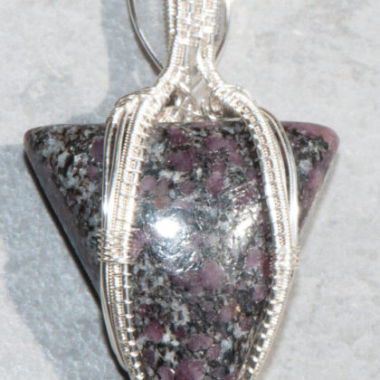 photo of triangular shaped ruby in granite stone wrapped in silver filled wire