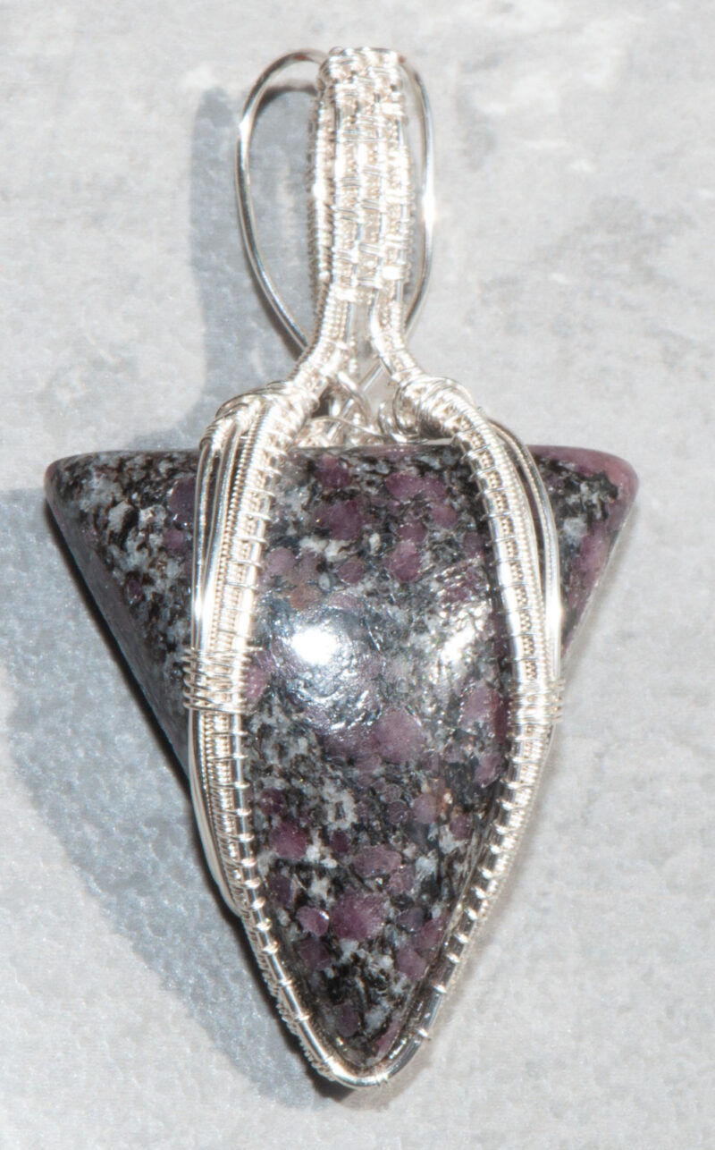 photo of triangular shaped ruby in granite stone wrapped in silver filled wire