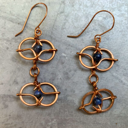 Photo of copper wire ovals with sodalite beads in the center fashioned into a matching pair of earrings.